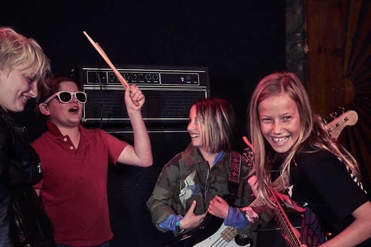 A group of School of Rock students smile in group music lessons