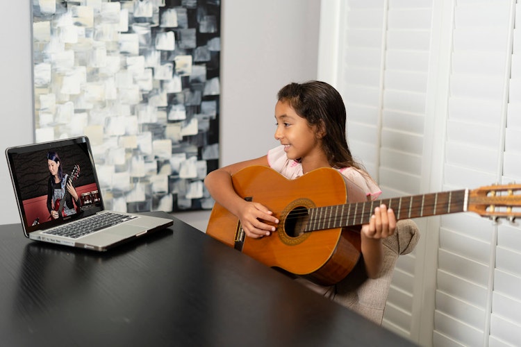 Student learning to play in online rock program for kids